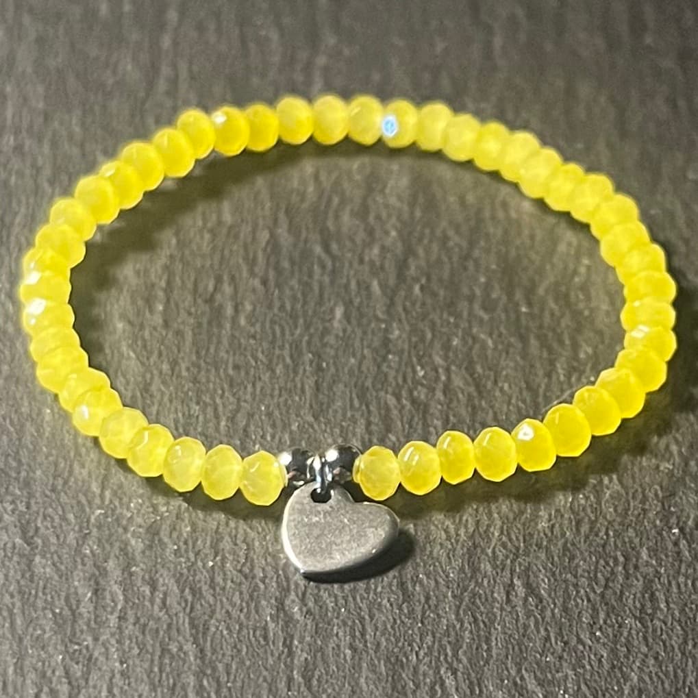Bracelet enfant en perles à facettes aux couleurs acidulées et d'un pendentif cœur en acier inoxydable argenté ou doré conçu sur mesure avec des perles