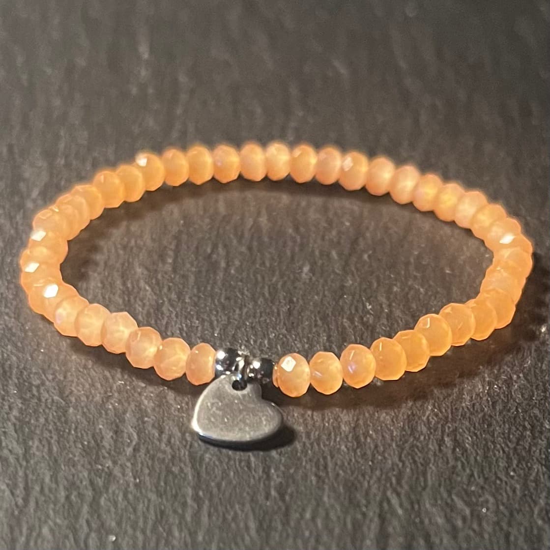 Bracelet enfant en perles à facettes aux couleurs acidulées et d'un pendentif cœur en acier inoxydable argenté ou doré conçu sur mesure avec des perles