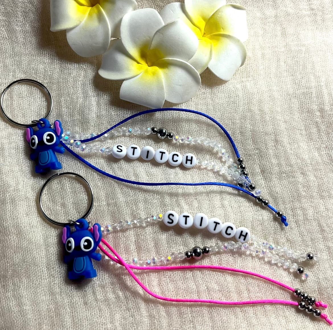 Porte-clé STITCH existe bleu électrique ou fuchsia avec des perles irisées de 3 mm, agrément é de pendentifs blancs avec l'inscription stitch noires et de perles en acier inoxydable. Fabrication Française, atelier situé à Aix en Provence
