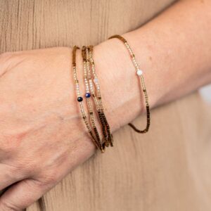 Bracelet femme en perles japonaises dorées et champagne avec perle à facettes centrale, monté sur fil élastique résistant, élégant et lumineux, adaptable à tous les poignets. Perles de deux milimétres