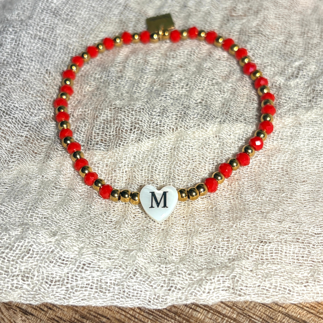Bracelet femme en perles à facettes de différents coloris, rouge, beige, corail, marine et turquoise, de perles dorées en acier inoxydable et d'un pendentif cœur en véritable nacre de coquillage orné d'une initiale conçu sur mesure avec des perles de trois millimètres fabriquée à la main à Aix-en-Provence