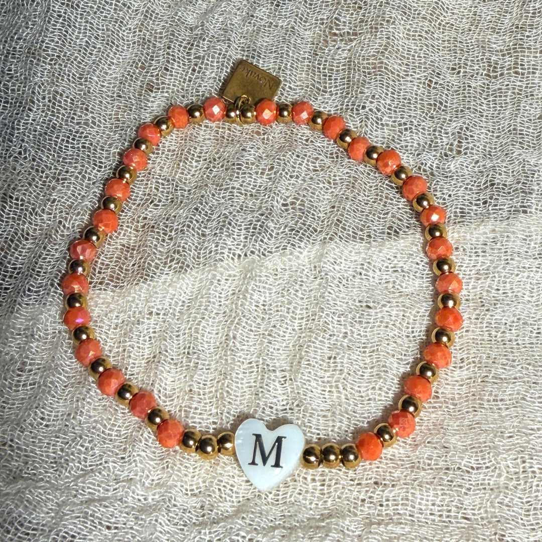 Bracelet femme en perles à facettes de différents coloris, rouge, beige, corail, marine et turquoise, de perles dorées en acier inoxydable et d'un pendentif cœur en véritable nacre de coquillage orné d'une initiale conçu sur mesure avec des perles de trois millimètres fabriquée à la main à Aix-en-Provence